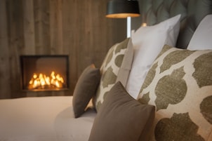 Een gezellige kamer met een open haard, een bank met gestreepte kussens en een moderne lamp.