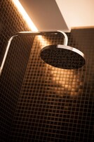 A showerhead with a curved design, mounted on a wall with a grid pattern.