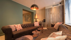 Een moderne woonkamer met een hoekbank, ronde salontafels en een hanglamp.