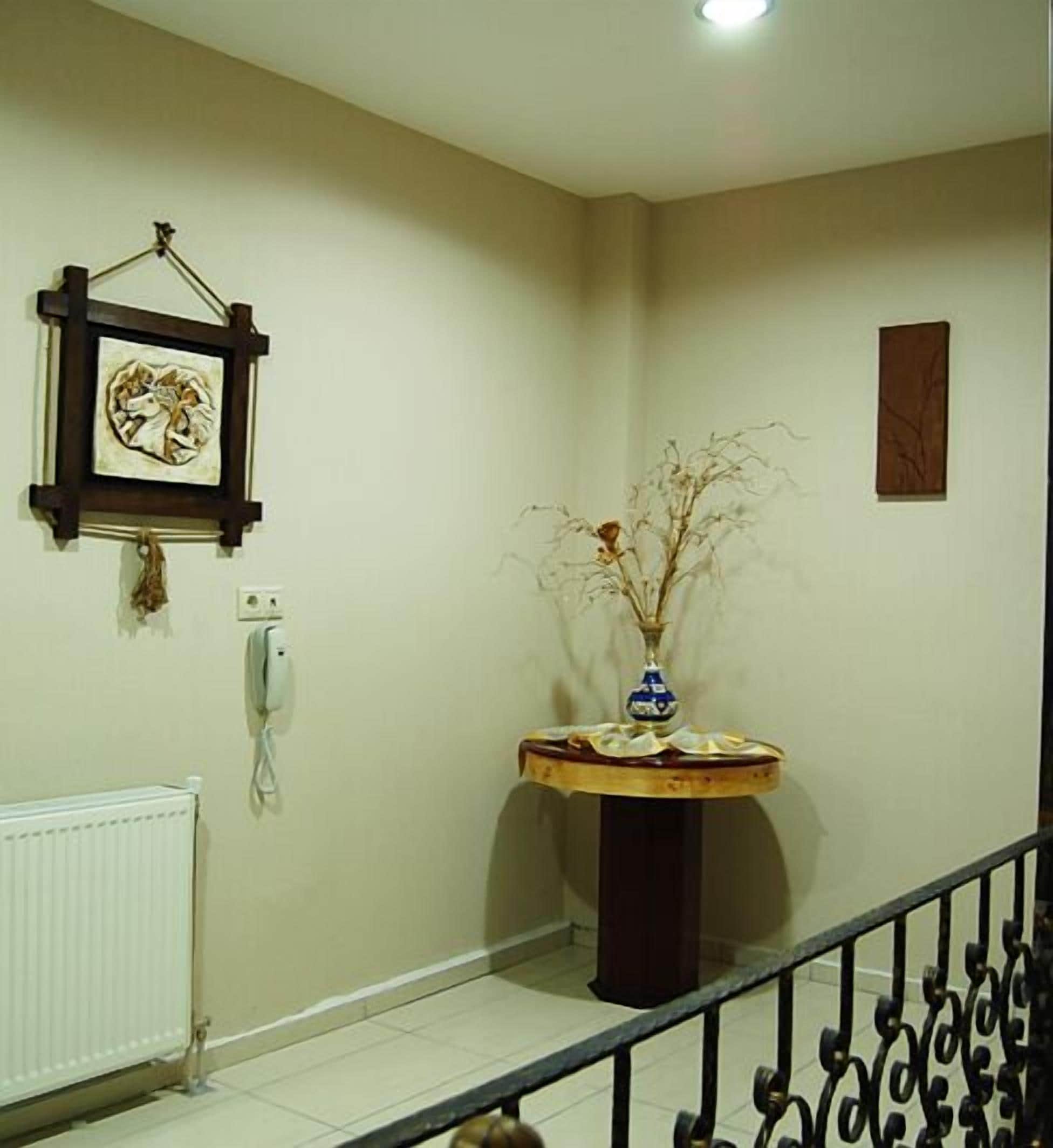 A hallway with a round table, a framed picture, a telephone, and a radiator.