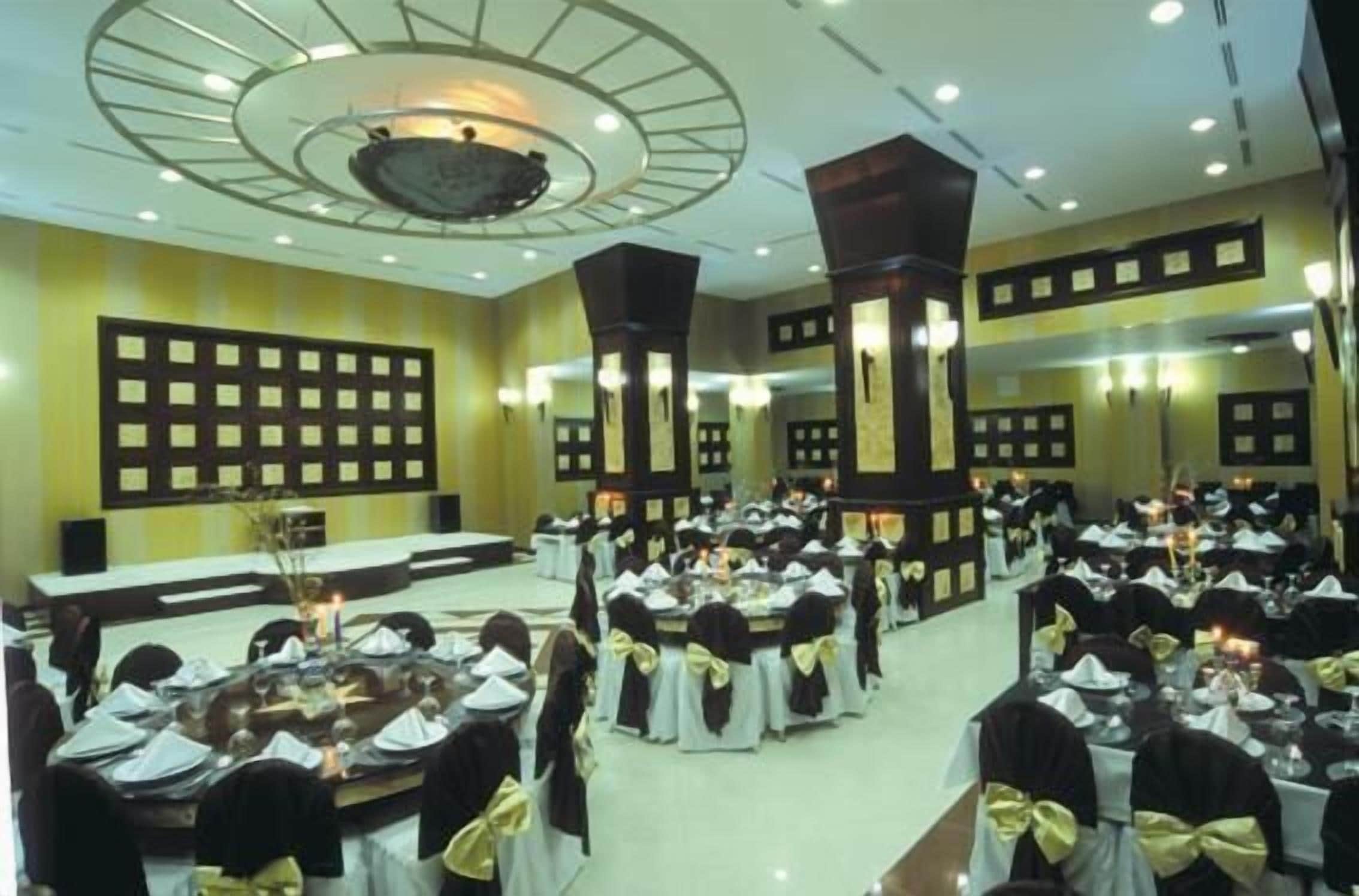 A banquet hall with round tables, black and white tablecloths, and yellow sashes.