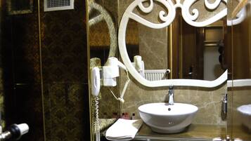 Un baño con pared de mármol, un lavabo blanco, un mueble de tocador con cajones, un espejo y un inodoro.