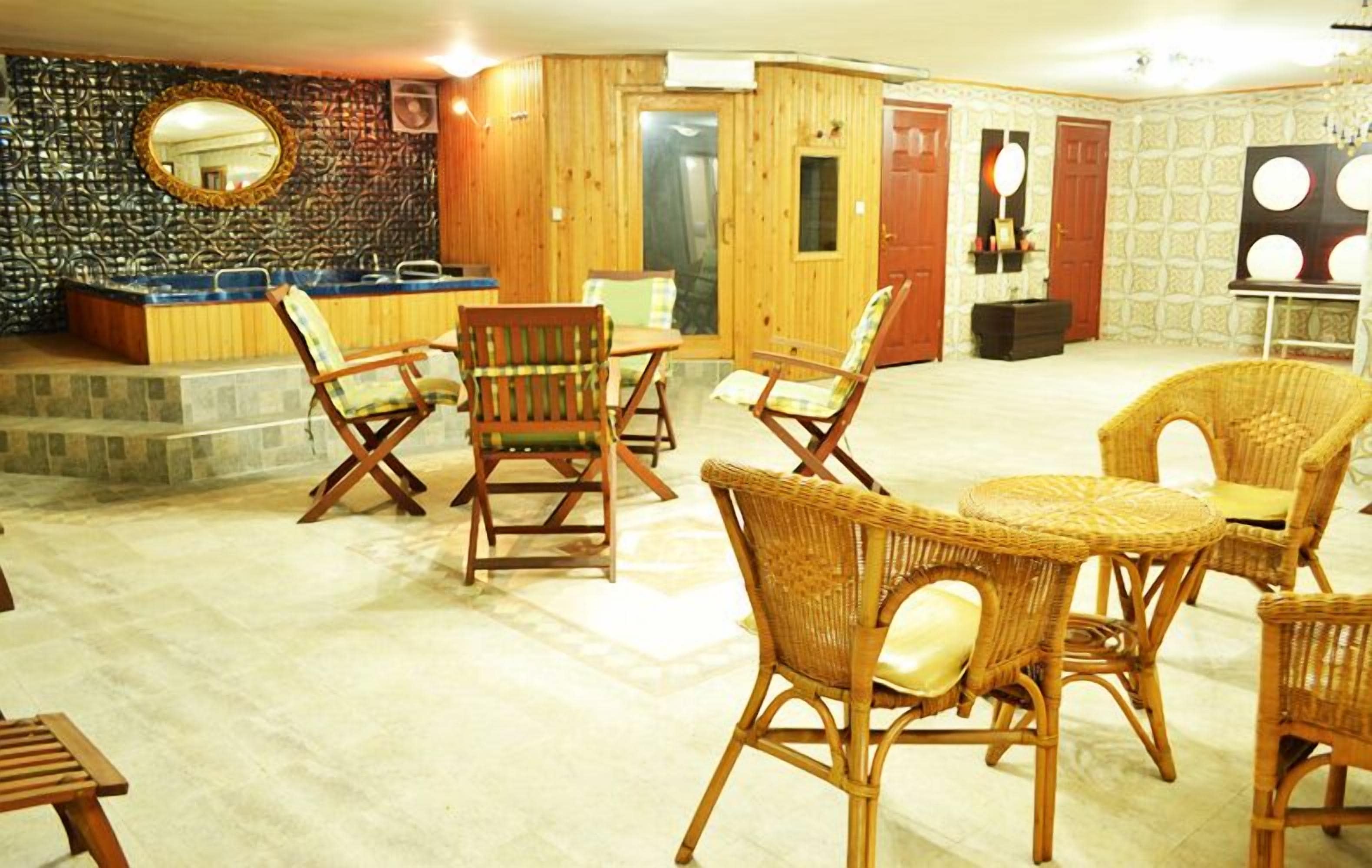 Un vestíbulo con muebles de mimbre, un mostrador de recepción y un espejo en la pared.