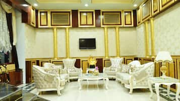 Una sala de estar lujosa con paneles dorados ornamentados, un televisor de pantalla plana grande y asientos mullidos.