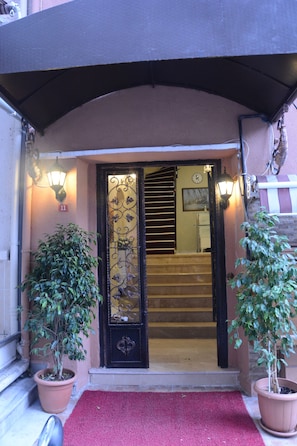 Stunning entrance with a black door, flanked by potted plants and a red carpet.