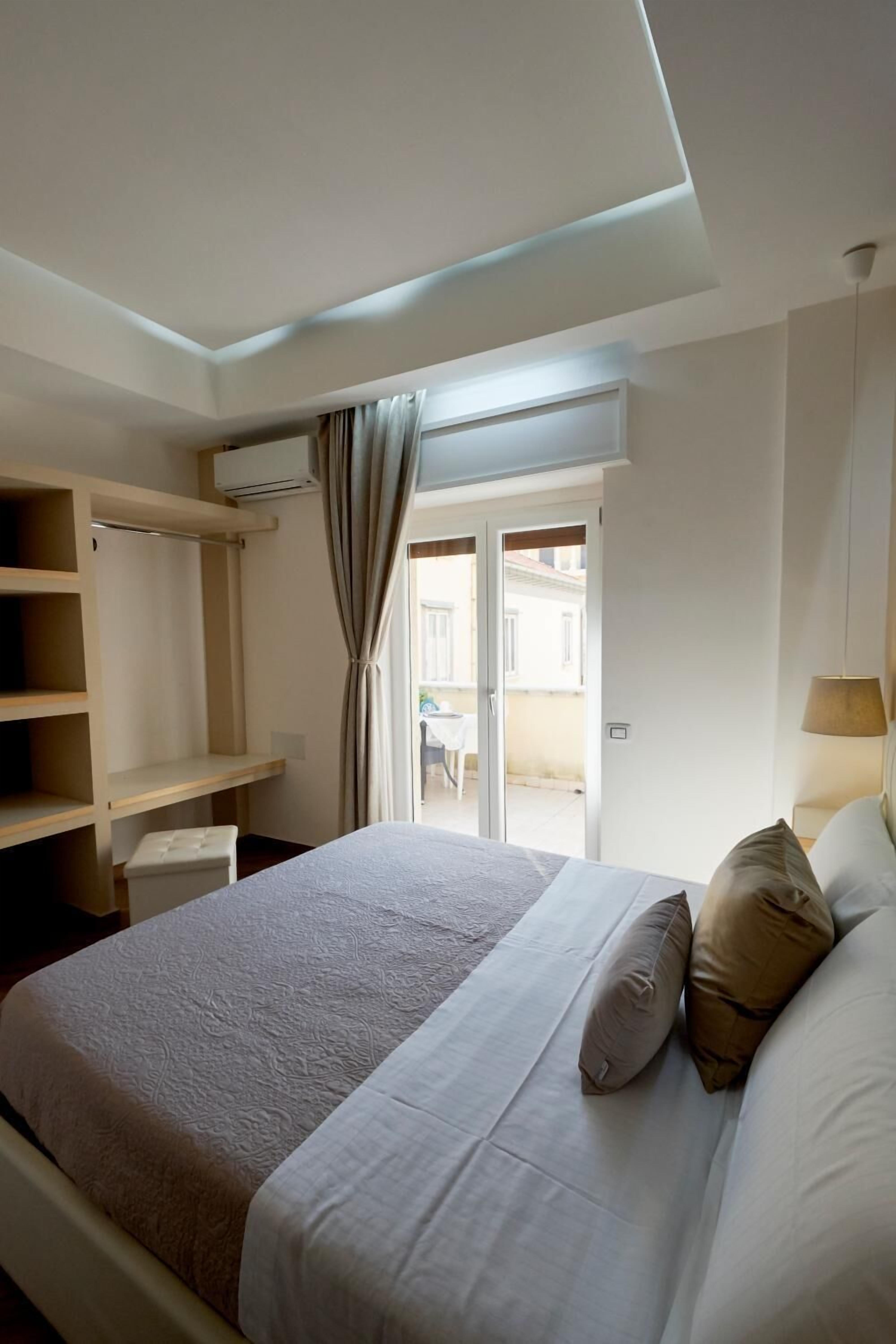 Une chambre à coucher avec un lit, une armoire, un bureau et une fenêtre avec des rideaux.
