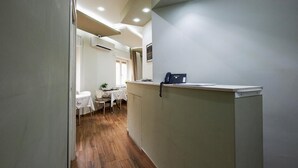 A hallway with a reception desk, a dining area with a table and chairs, and a window with curtains. - 360 Hospitality (Salerno)