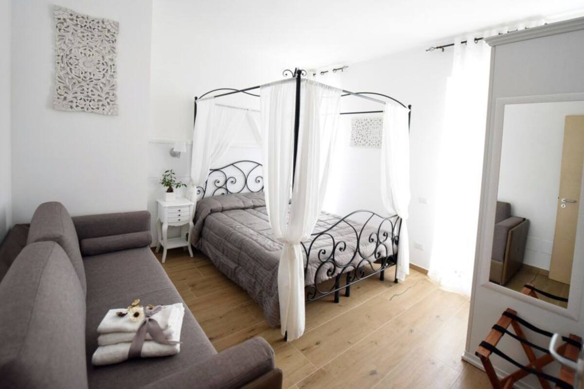 Une chambre à coucher avec un lit à baldaquin, un canapé, une table de chevet et un miroir.