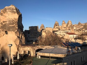 A historic building with a stone facade, a courtyard, and a view of unique rock formations in the background.
