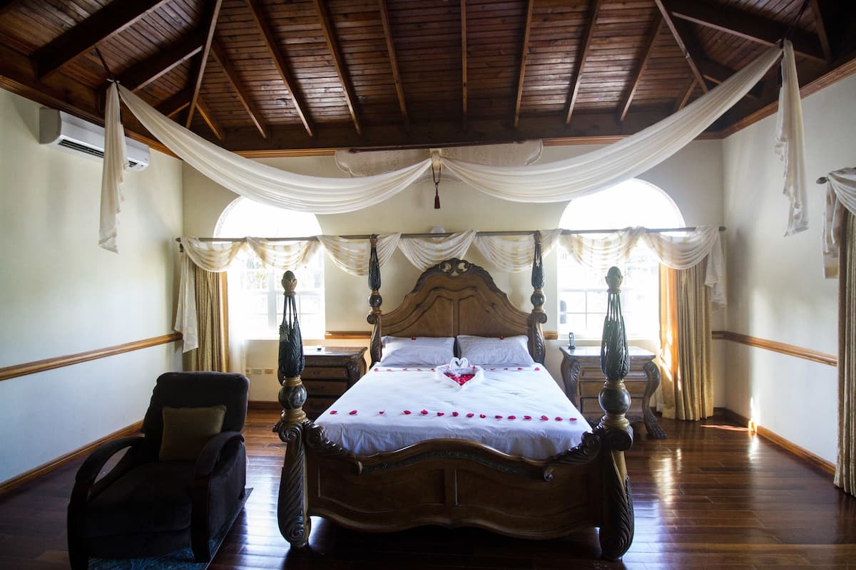 A four-poster bed with a white bedspread, a wooden headboard, and draped curtains.