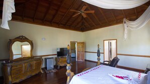 A spacious bedroom with a large bed, wooden furniture, a ceiling fan, and a television. - Steel Love Villa (Montego Bay)