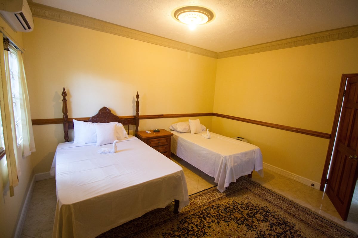 A hotel room with two beds, a wooden headboard, a nightstand, and a patterned rug.