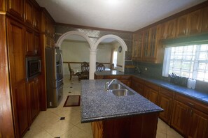 A kitchen with wooden cabinets, a granite countertop, a stainless steel sink, and a window with decorative glass.