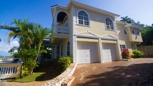A two-story house with a garage, a balcony, and a well-maintained garden. - Steel Love Villa (Montego Bay)