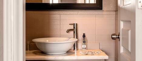 A bathroom with a white sink, a mirror above it, and a door to the right.