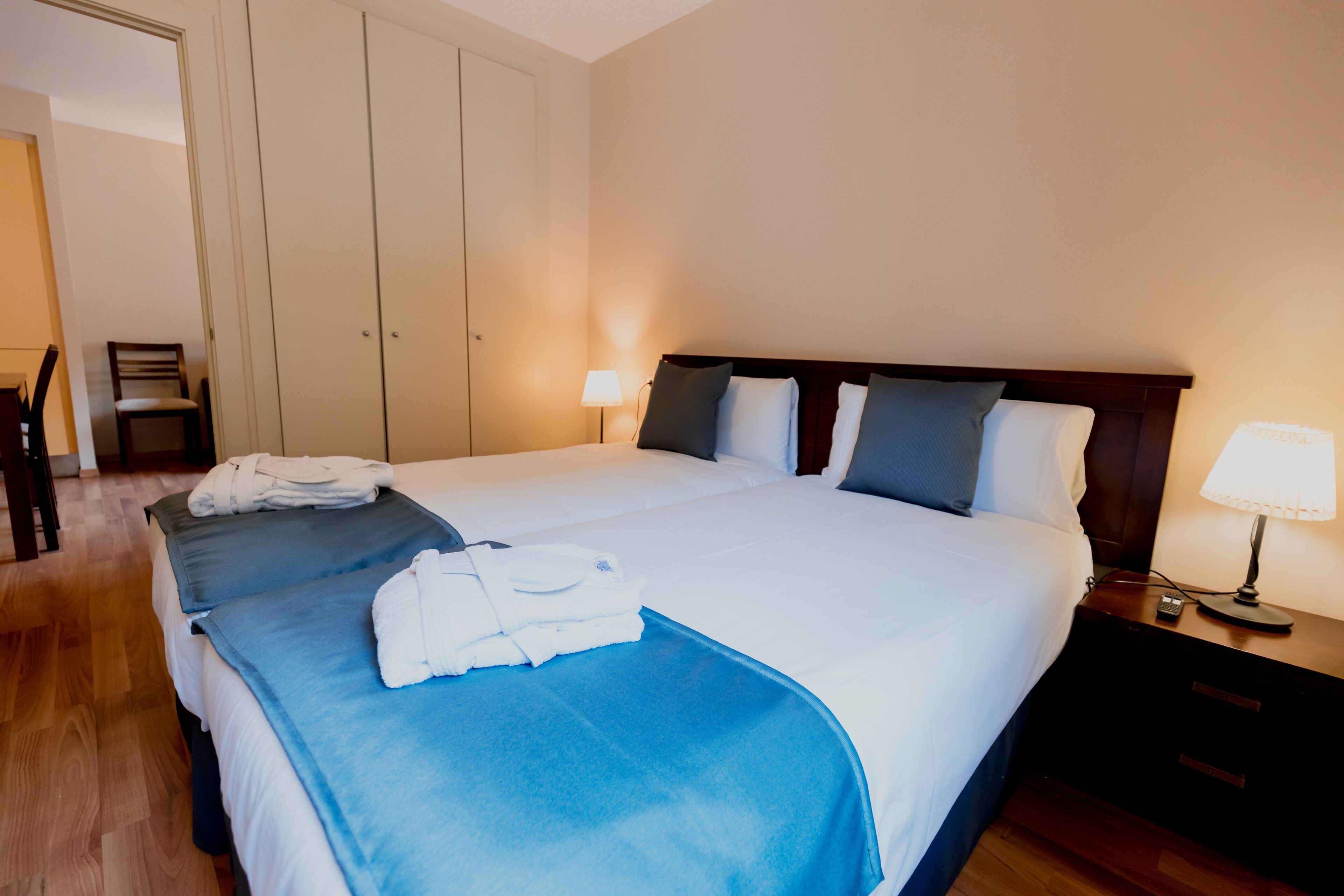 A hotel room with a large bed, two bedside tables, a chair, and a wardrobe.