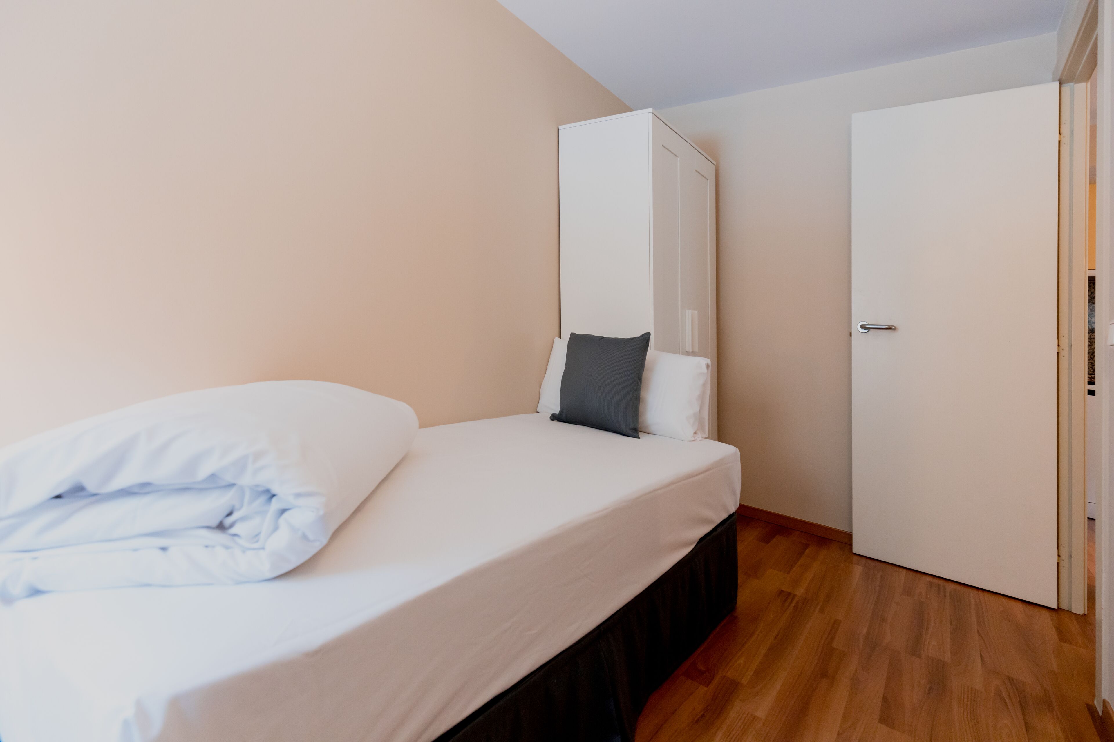 Un dormitorio con cama, armario y puerta.