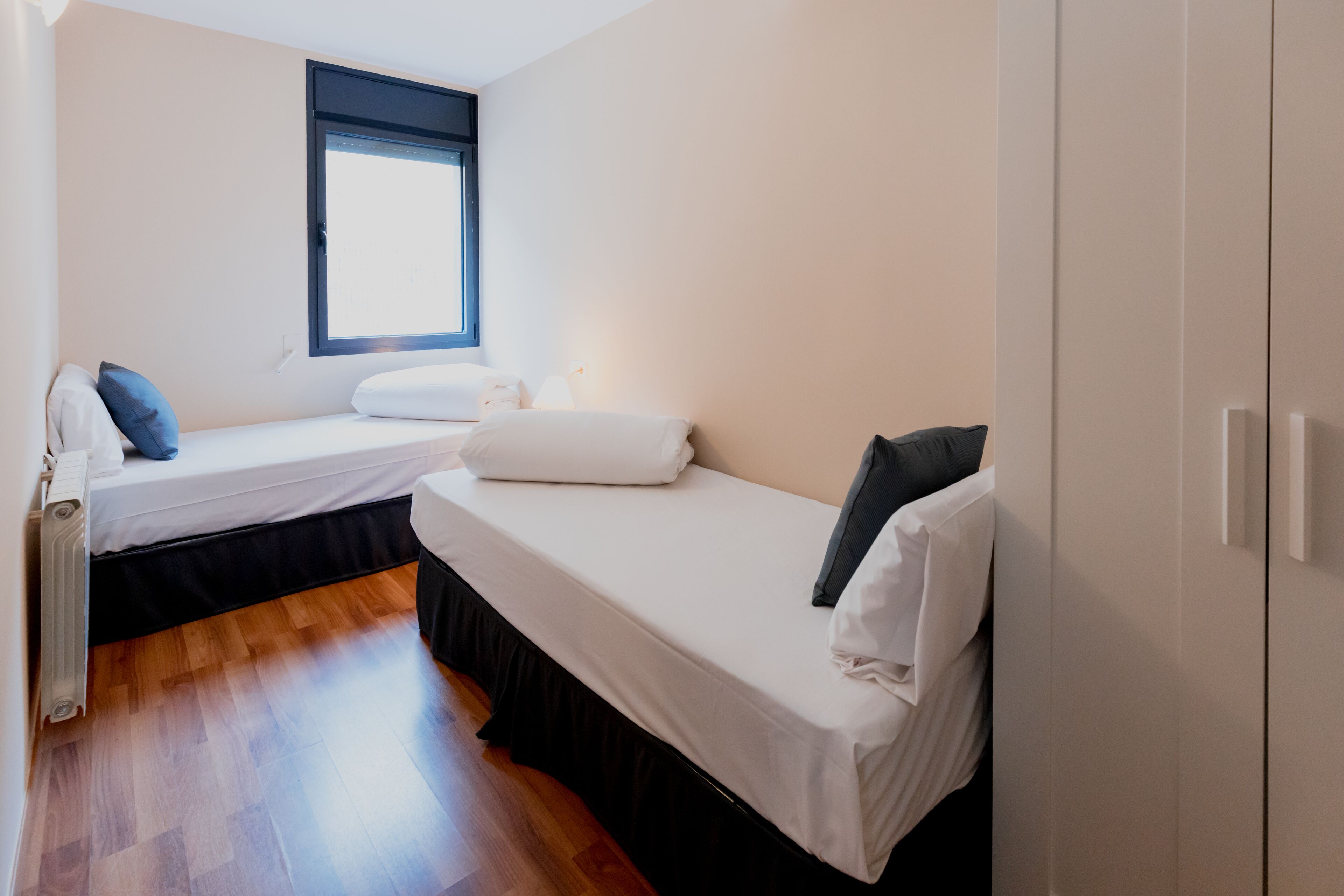 Ein Schlafzimmer mit zwei Betten, einem Fenster und einer Heizung.