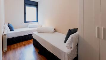 A bedroom with two beds, a window, and a radiator.