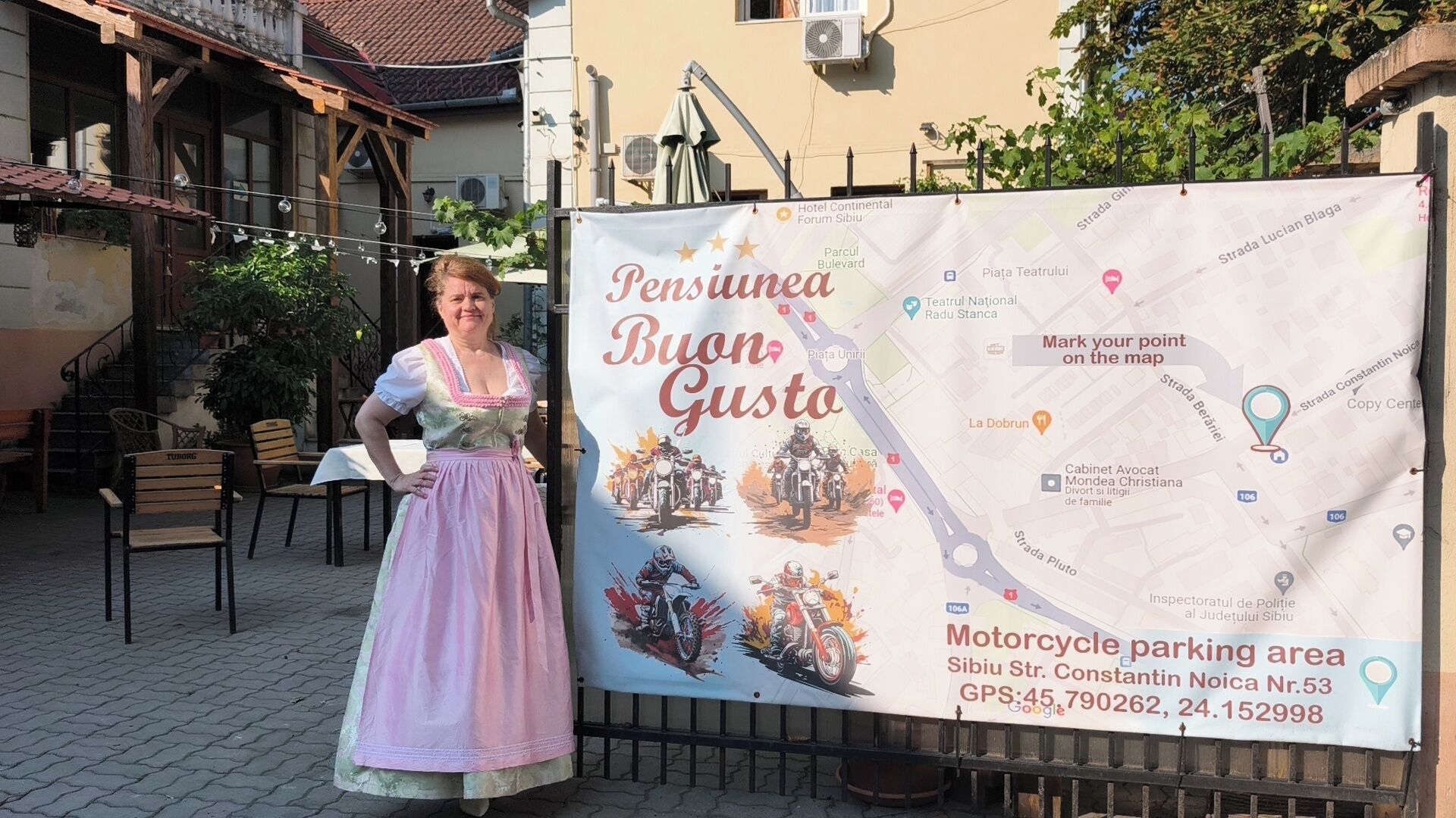 Eine Frau in traditioneller Kleidung steht vor einer Karte mit einem Schild für einen Motorradparkplatz.