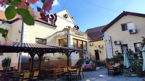 A courtyard with outdoor seating, a covered area, and a building with a balcony. - Pension Buon Gusto Sibiu - motorcycle friendly (Sibiu)