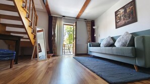 A spacious living room with a wooden staircase, a sofa, and a painting on the wall. - Pension Buon Gusto Sibiu - motorcycle friendly (Sibiu)