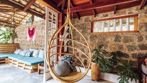 A rustic room with a hanging chair, a wooden bench, and a stone wall. - Santa Smart Hotel (Ilhabela)