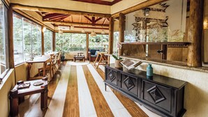 A spacious room with wooden flooring, a large window, a wooden table, and a cabinet. - Santa Smart Hotel (Ilhabela)