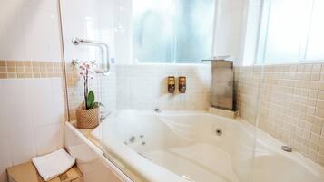Un baño moderno con una bañera grande, cabina de ducha de vidrio y una pequeña zona de estar.