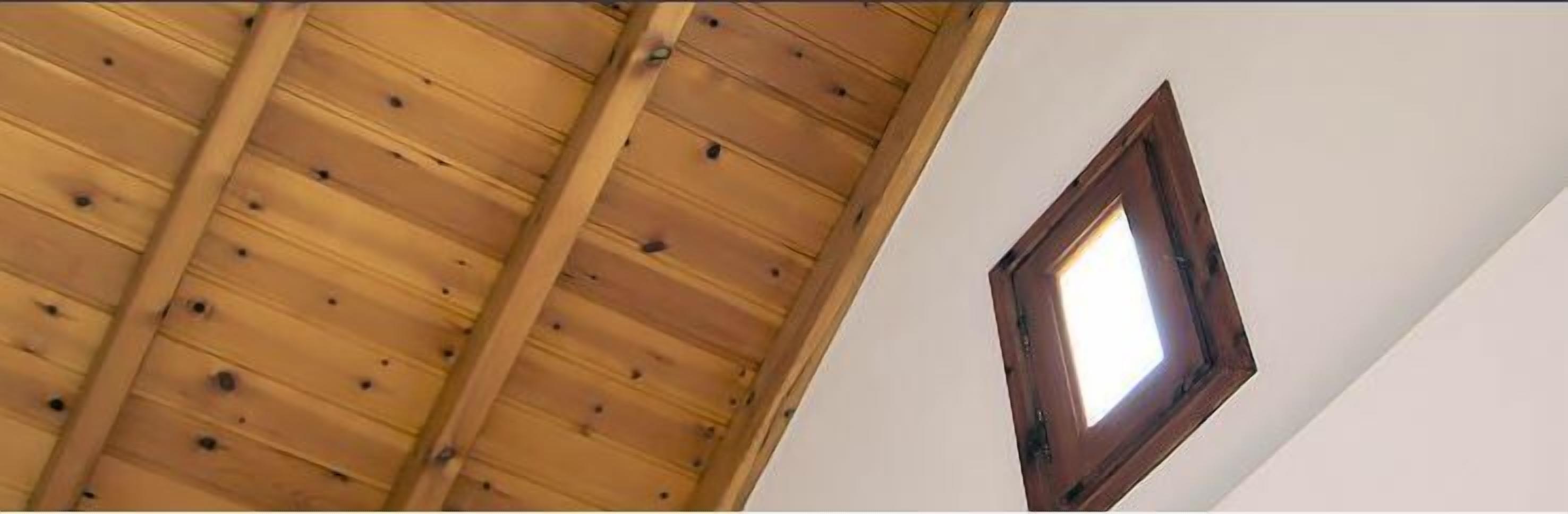 Una habitación con techo de madera inclinado y un ventanal pequeño.