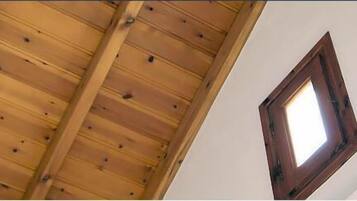 Una habitación con techo de madera inclinado y un ventanal pequeño.