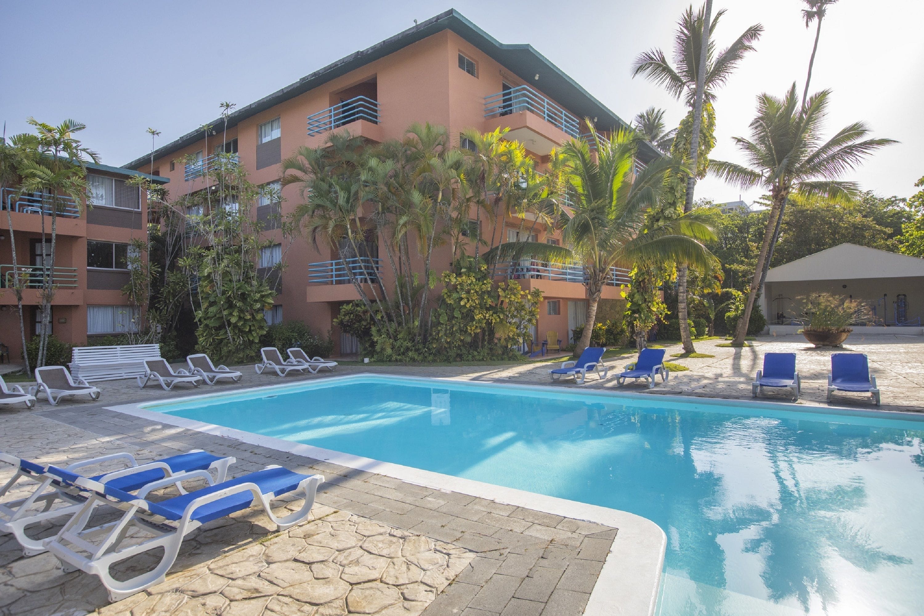 Un hôtel doté d’une piscine, de chaises longues et de palmiers.