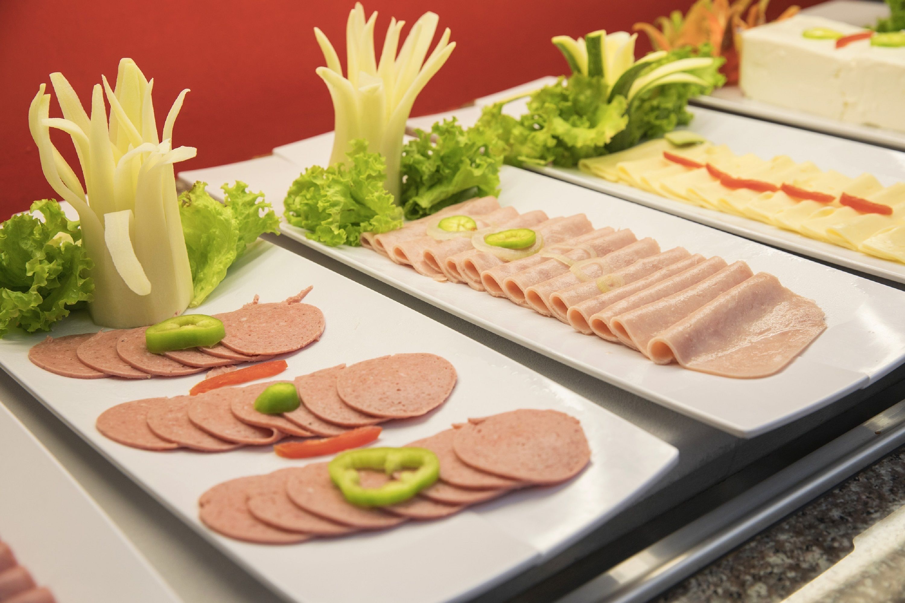 A buffet with various food items including sliced meats, vegetables, and cheese.