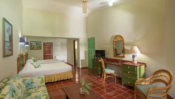 Una habitación de hotel con cama, escritorio, silla, cómoda y ventilador de techo.