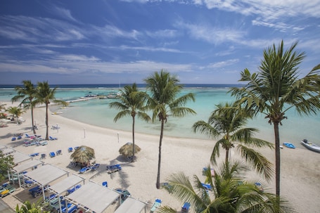 En la playa, arena blanca, sillas reclinables de playa, sombrillas