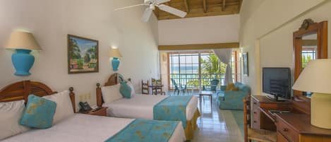 A hotel room with two beds, a TV, a desk, and a balcony with a view.