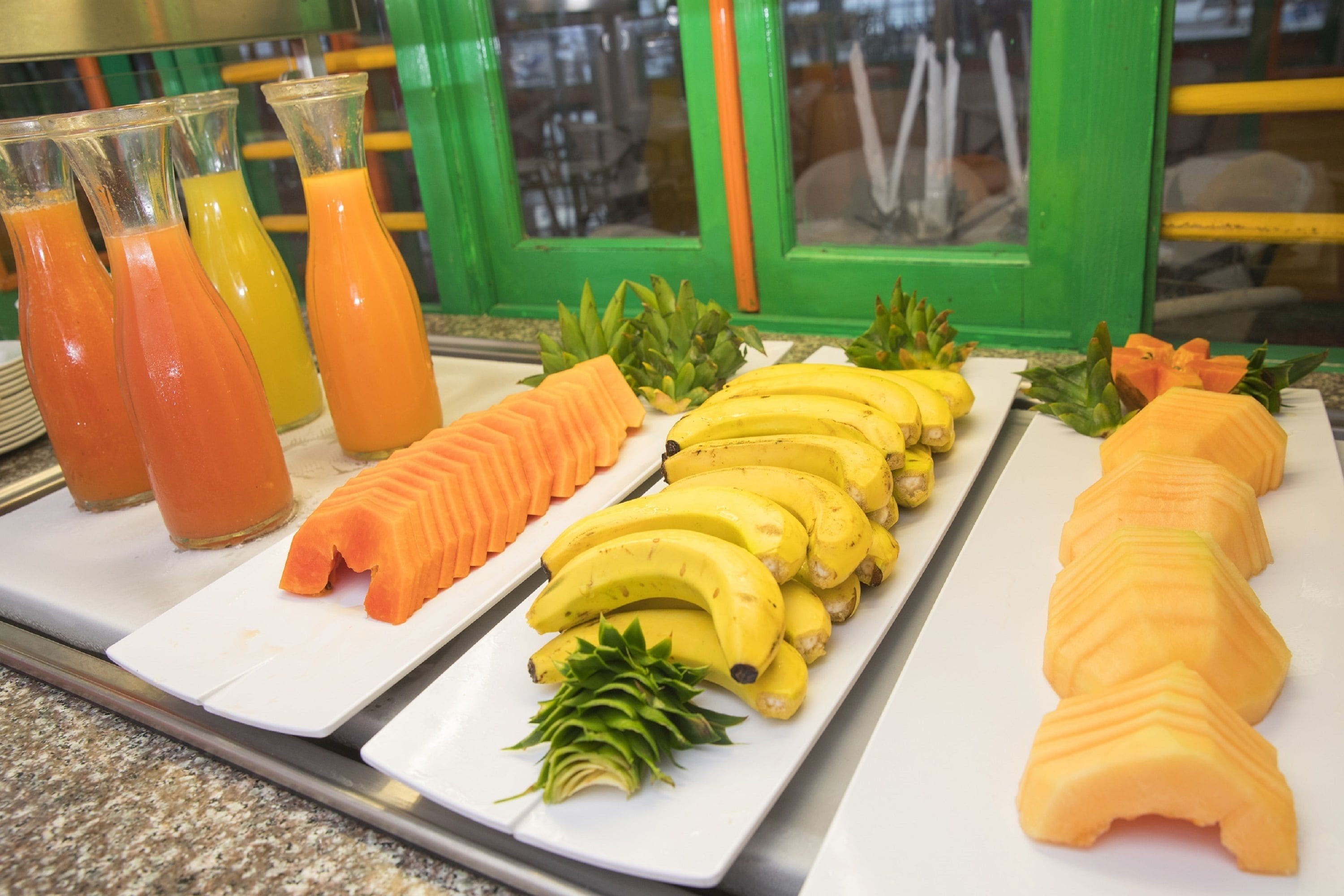 A breakfast buffet with sliced fruits and juices.