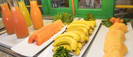 A breakfast buffet with sliced fruits and juices.