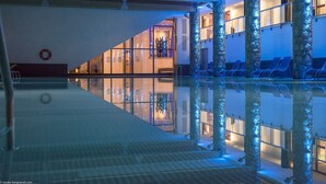 En swimmingpool med klart vatten, omgiven av stenpelare och solstolar.