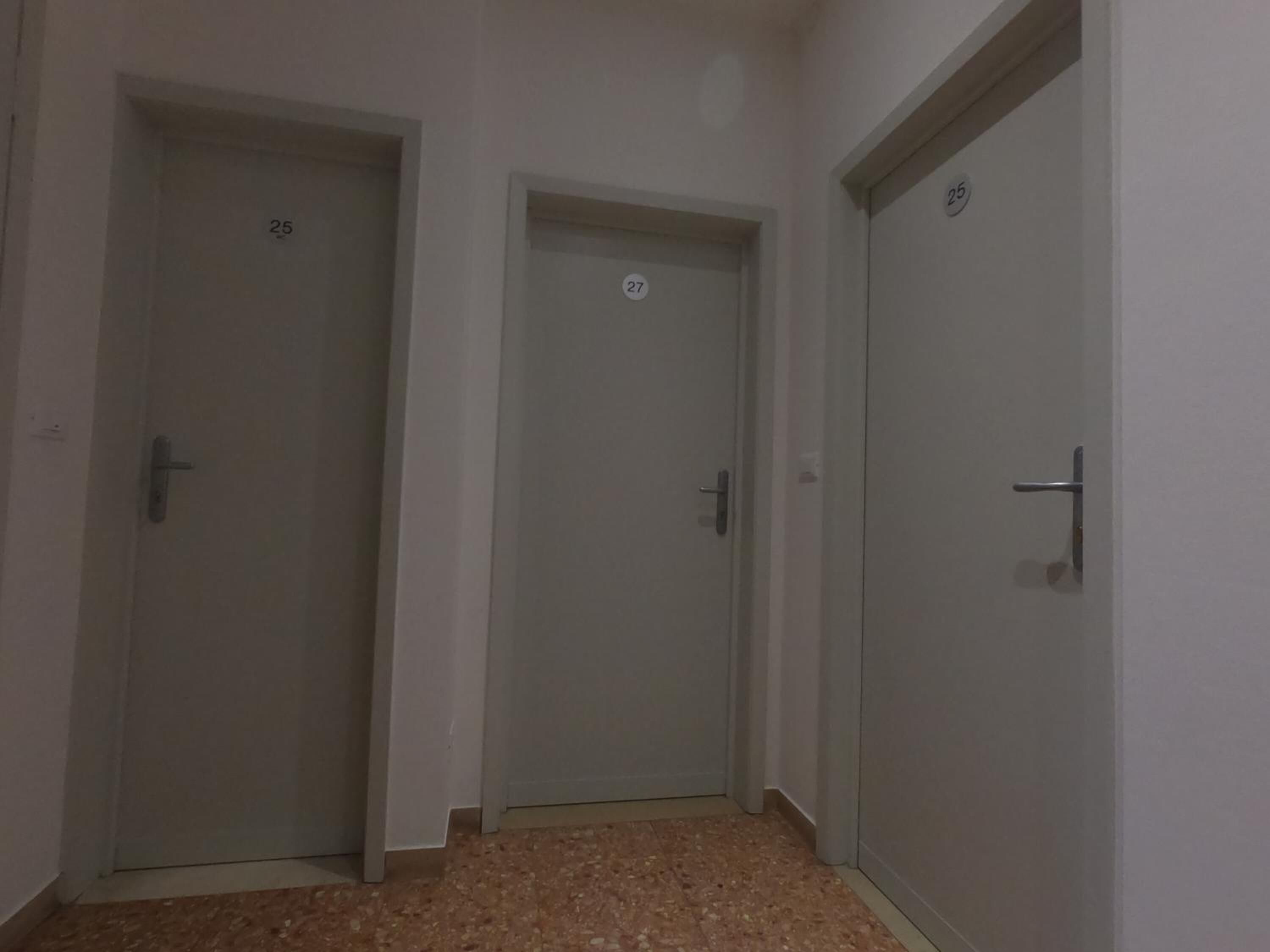 Un couloir avec trois portes, chacune portant un numéro.