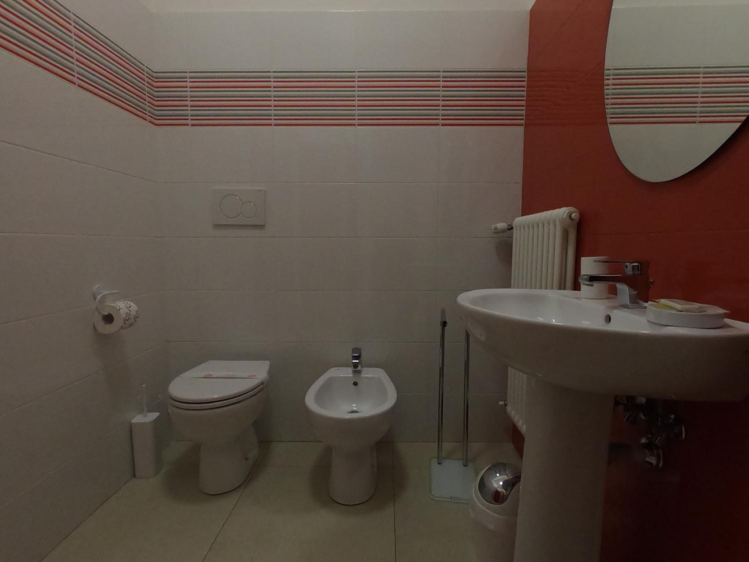 Une salle de bain équipée de toilettes, d’un bidet et d’un lavabo.