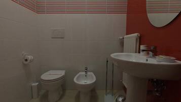 Une salle de bain équipée de toilettes, d’un bidet et d’un lavabo.