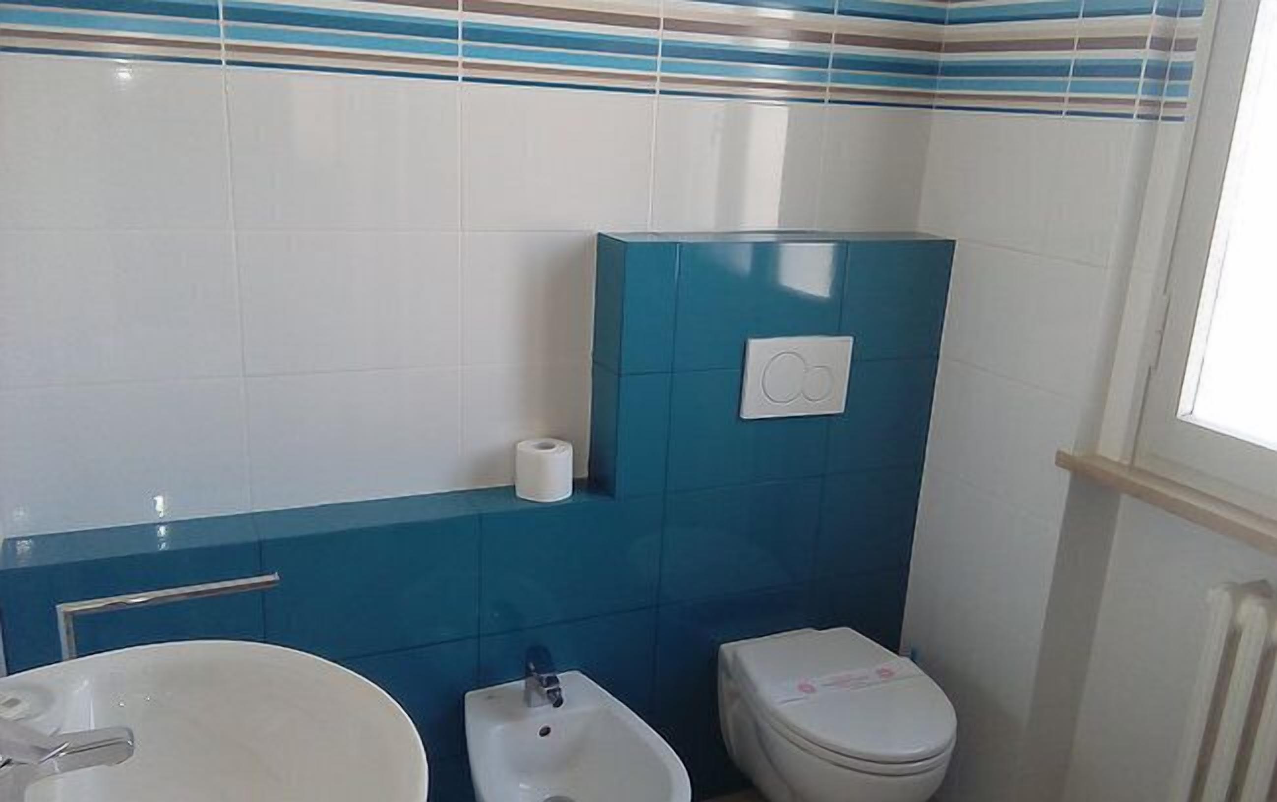 Ein Badezimmer mit einem weißen Waschbecken, einem Bidet und einer Toilette.