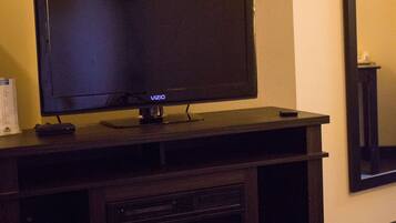 A flat-screen TV on a wooden entertainment center with a fireplace below.