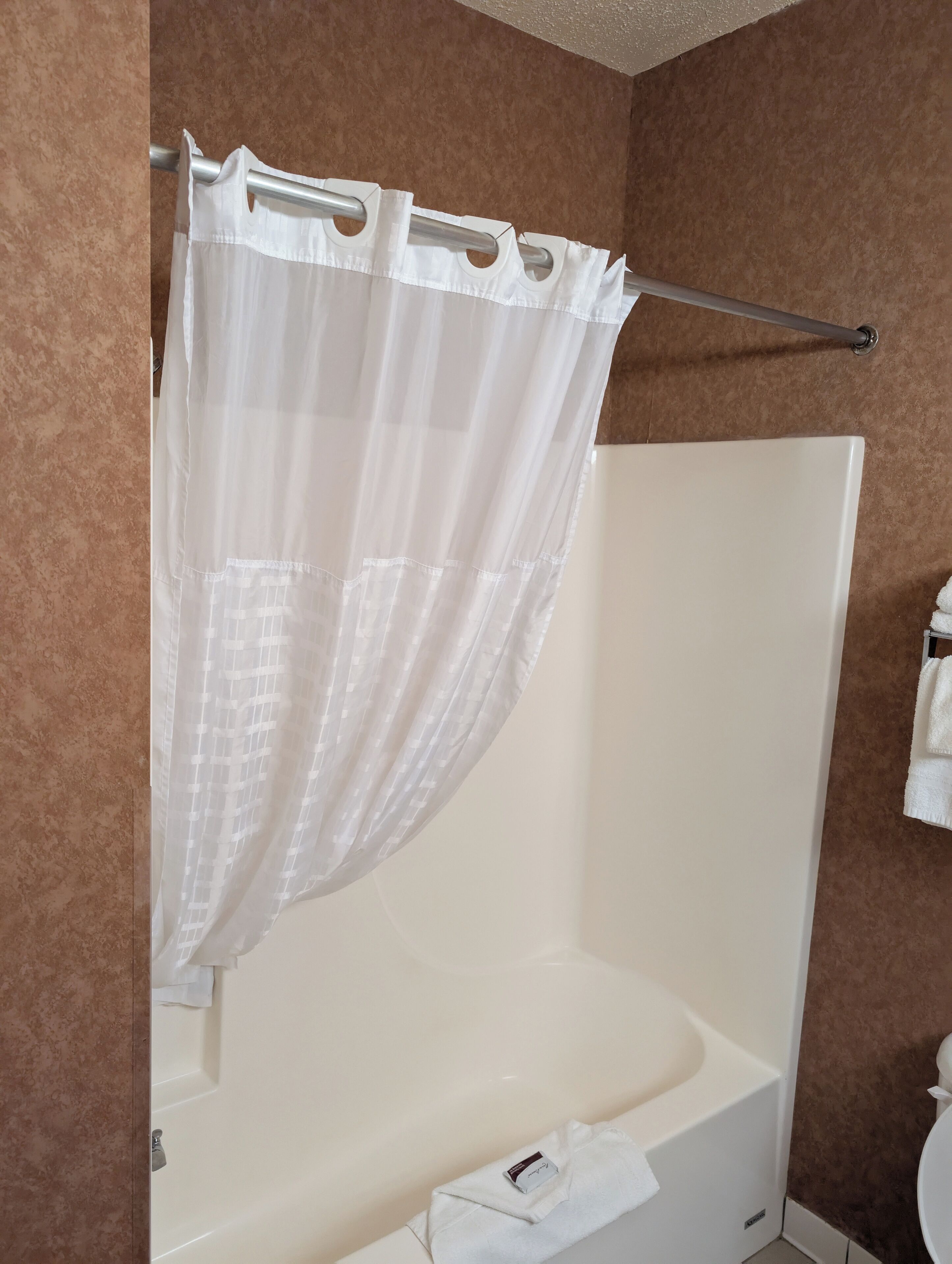 A bathroom with a shower curtain, a bathtub, and a towel rack.