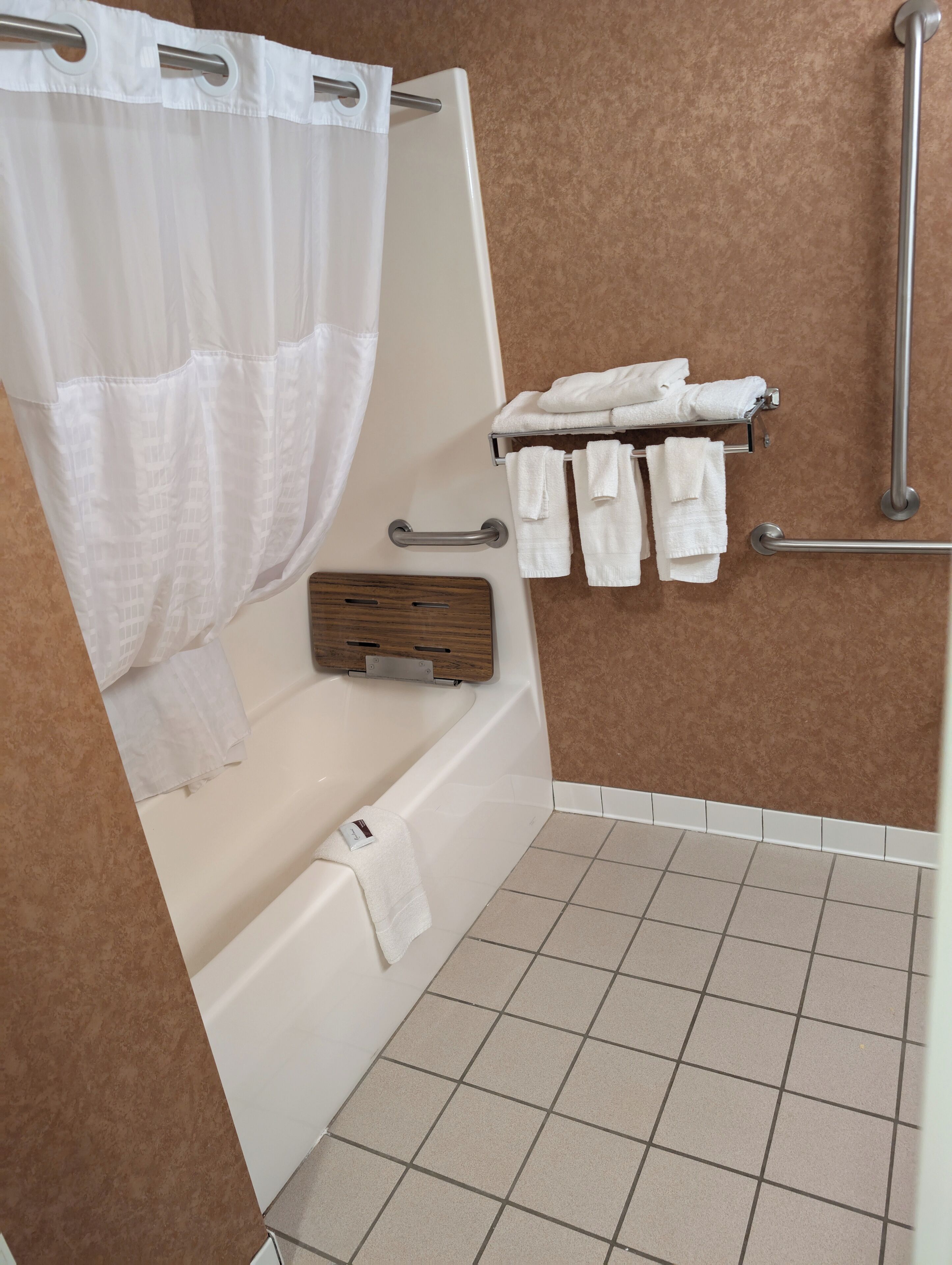 Un baño con bañera, zona de ducha y un perchero con varias toallas.