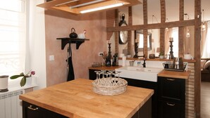 A kitchen with a wooden countertop, a sink, and a hanging light fixture. - Le Logis Aux Bulles (Verzy)
