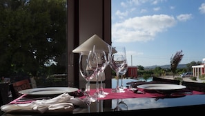 A dining table with wine glasses, plates, and cutlery, set against a scenic view of a pool and mountains. - Casa D'Edite (Chamusca)
