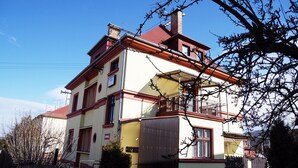 A multi-story building with a red roof, balconies, and a chimney. - Pension Lada (Karlovy Vary)