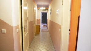 A hallway with a tiled floor, doors on both sides, and a bench in the distance. - Pension Lada (Karlovy Vary)